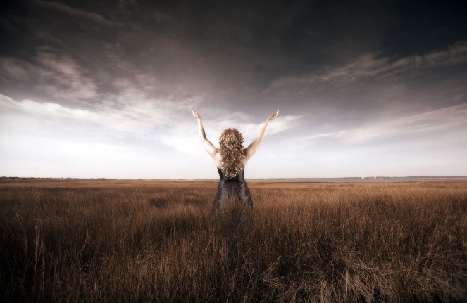 Woman lifting her hands up in a field